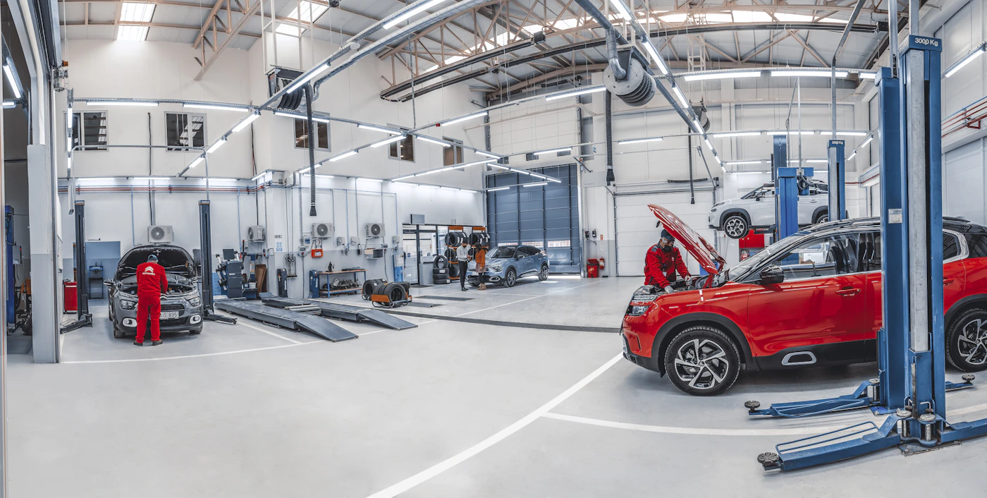 Bright modern vehicle repair facility with mechanics servicing cars