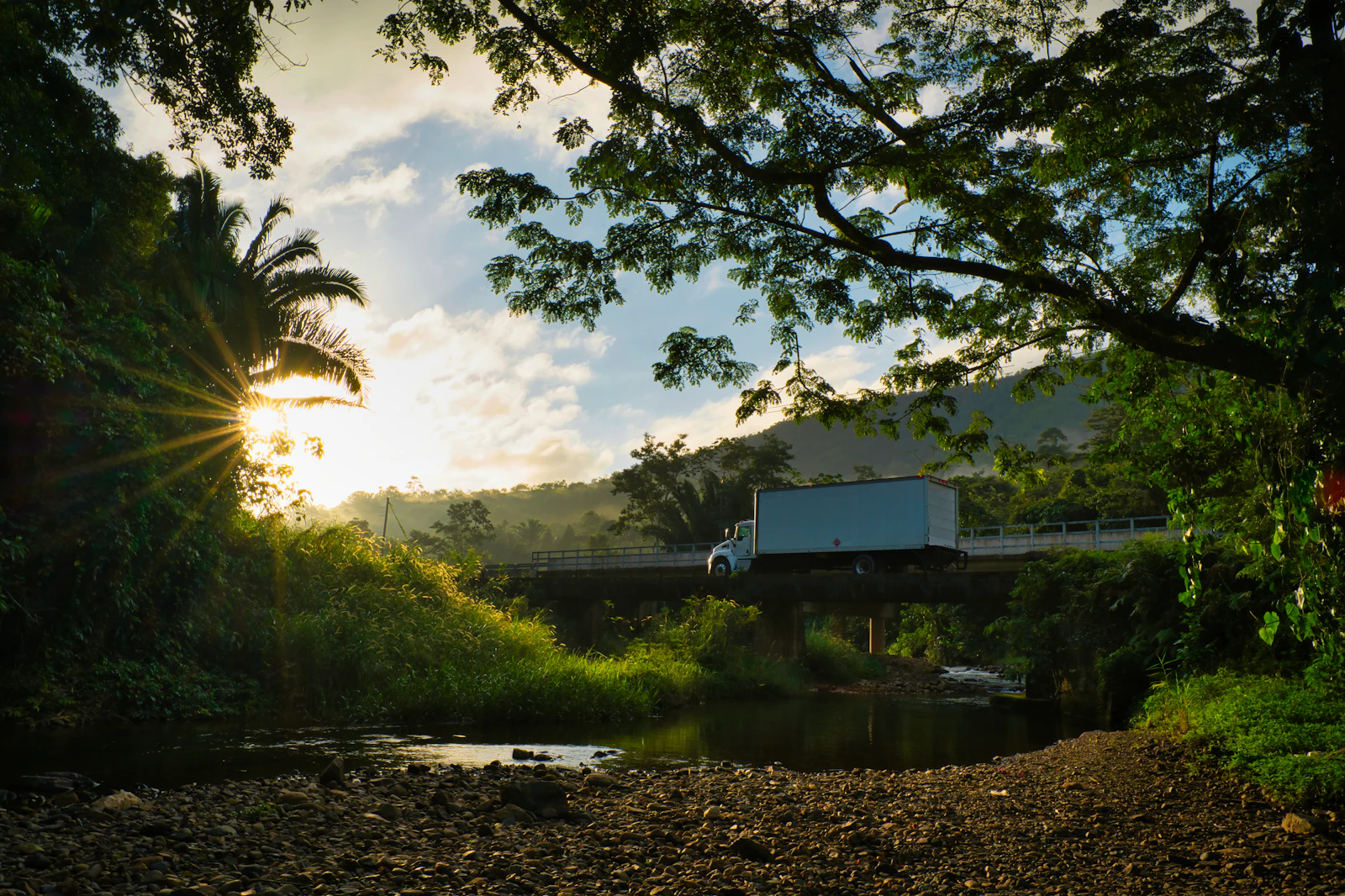 Truck crossing a bridge at golden hour, representing long-distance transport